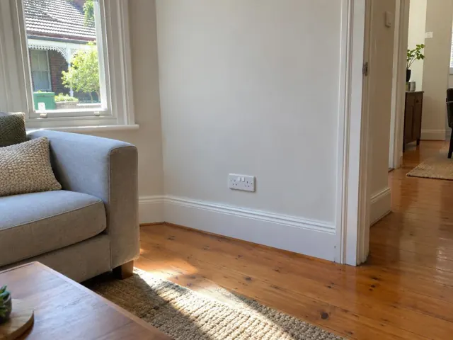 White double power point on a painted wall in a living room with timber floors in Petersham