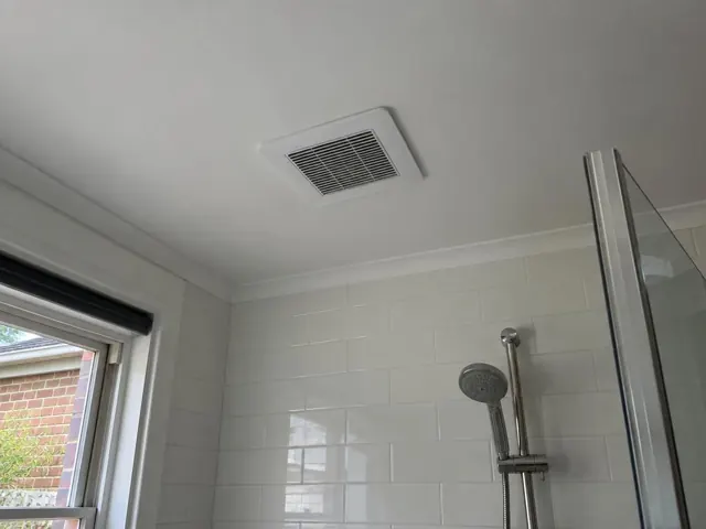 Bathroom ceiling exhaust fan above tiled shower walls with window and glass screen in Stanmore